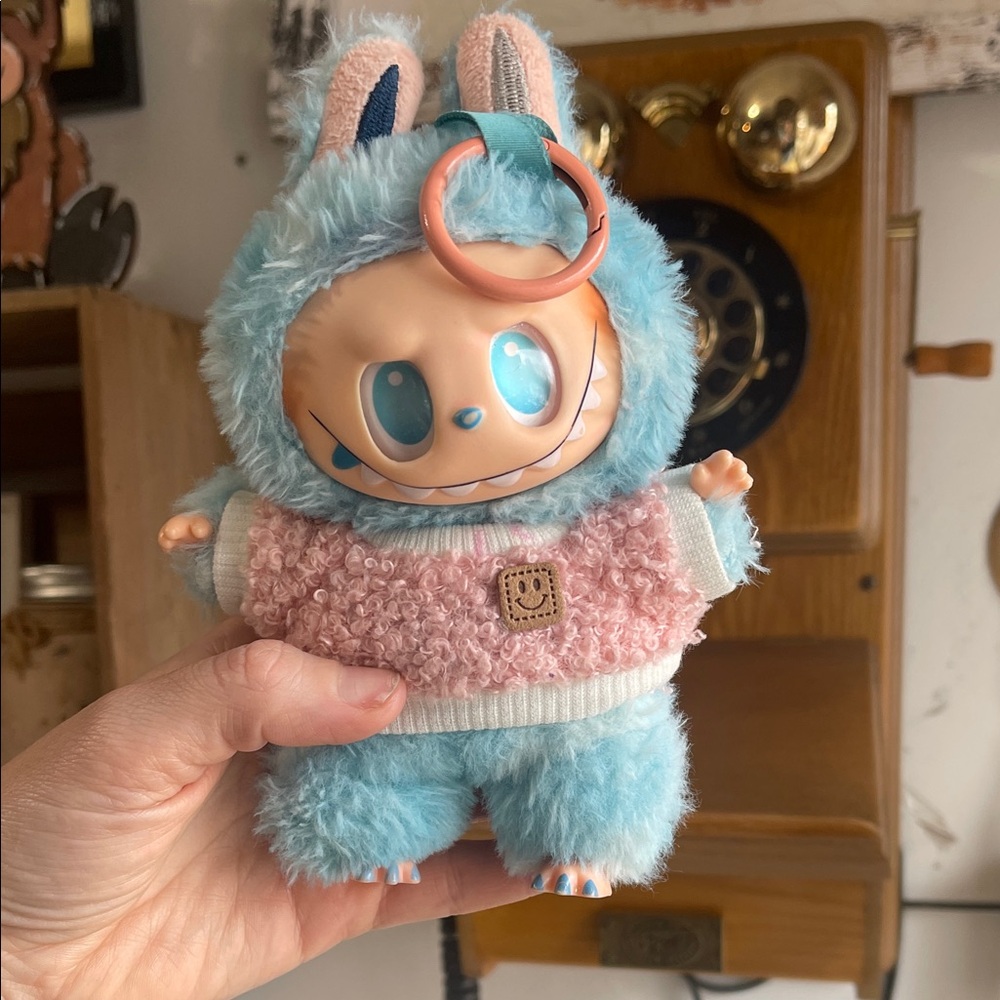 The Monsters Labubu collectible figure blue fuzzy bunny outfit with pink sweater